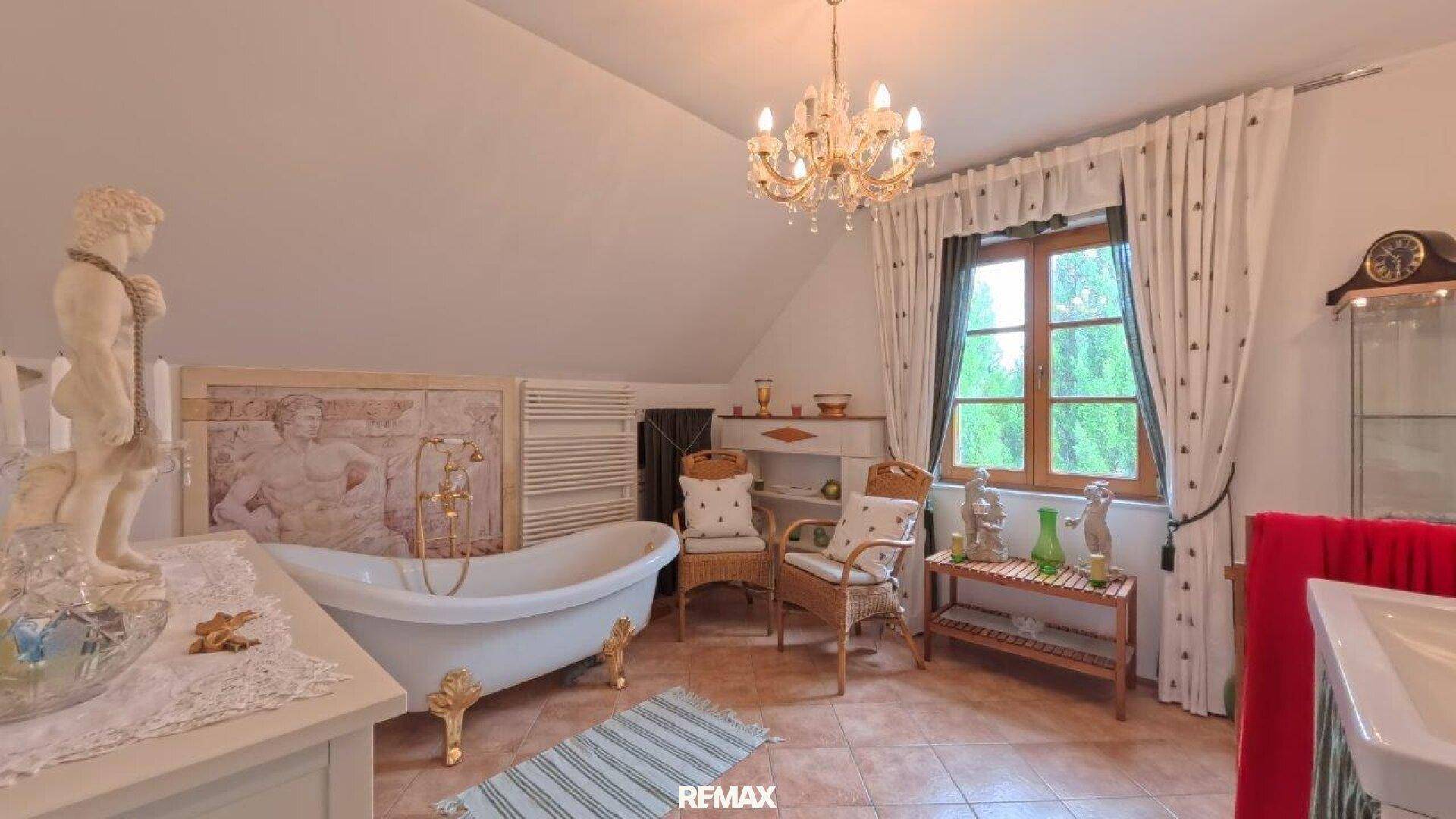 Geräumiges Badezimmer im Dachgeschoss mit freistehender Badewanne und Fenster.