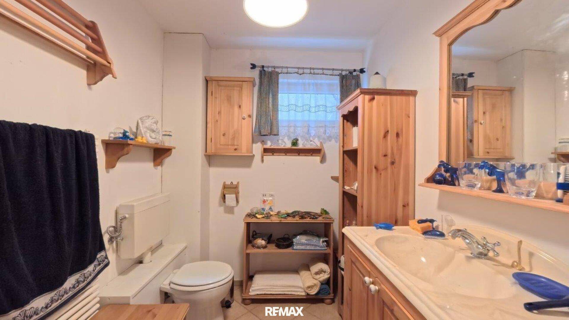 Rustikales Badezimmer mit Holzmöbeln, Waschtisch und Fenster.