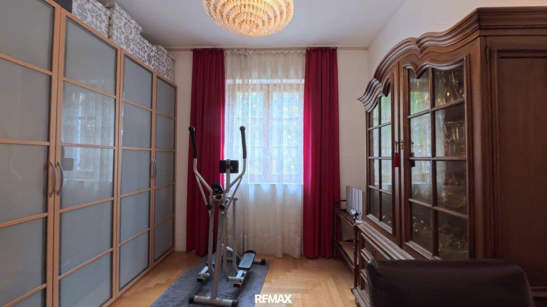 Zimmer mit Fitnessgerät, großem Kleiderschrank und klassischem Holzschrank.