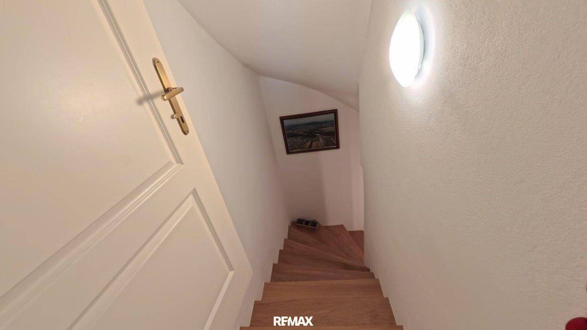 Holztreppe führt in ein tiefer gelegenes Stockwerk.