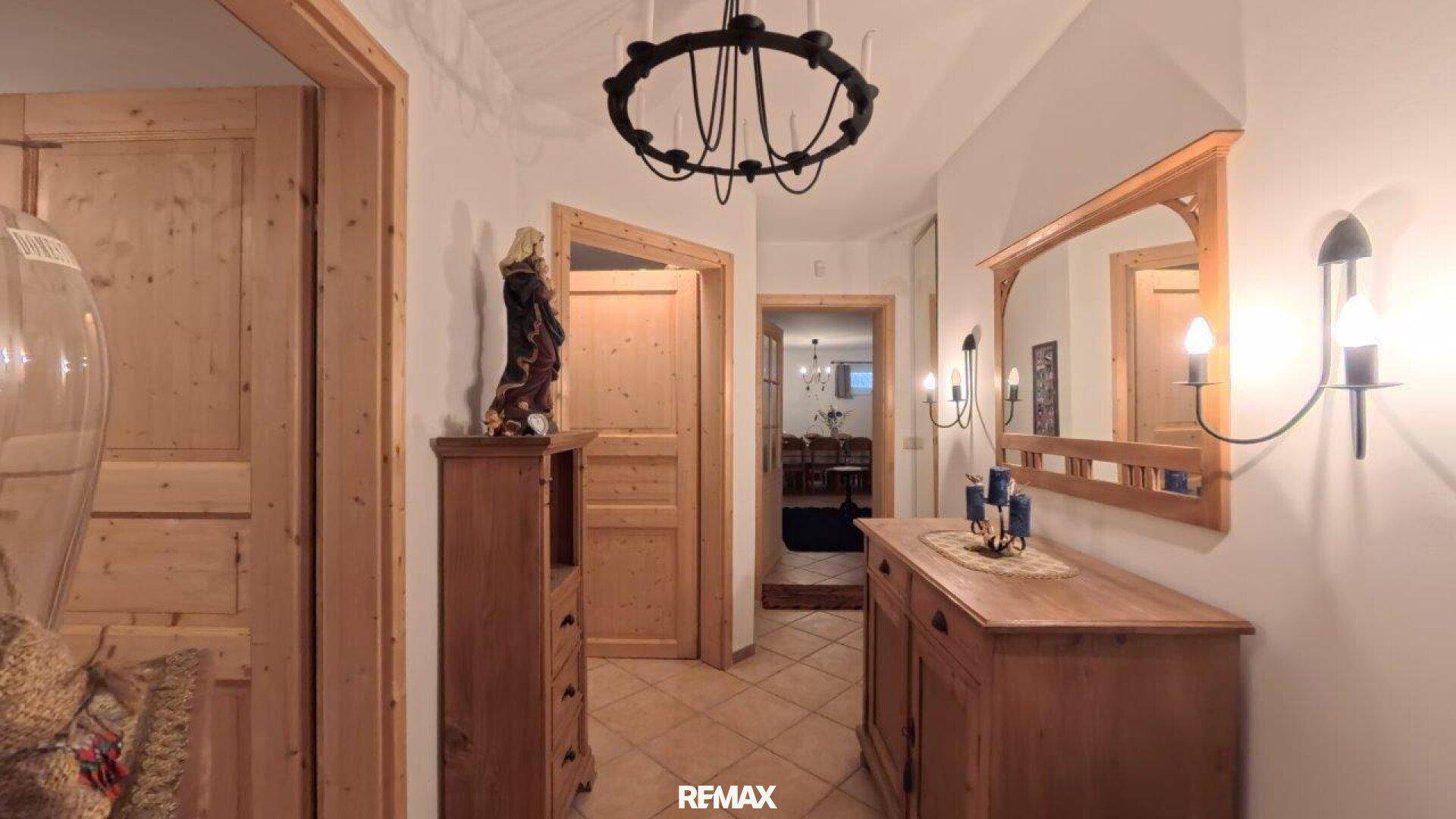 Rustikaler Flur mit Holzmöbeln, Terrakottafliesen und schmiedeeisernem Kronleuchter.