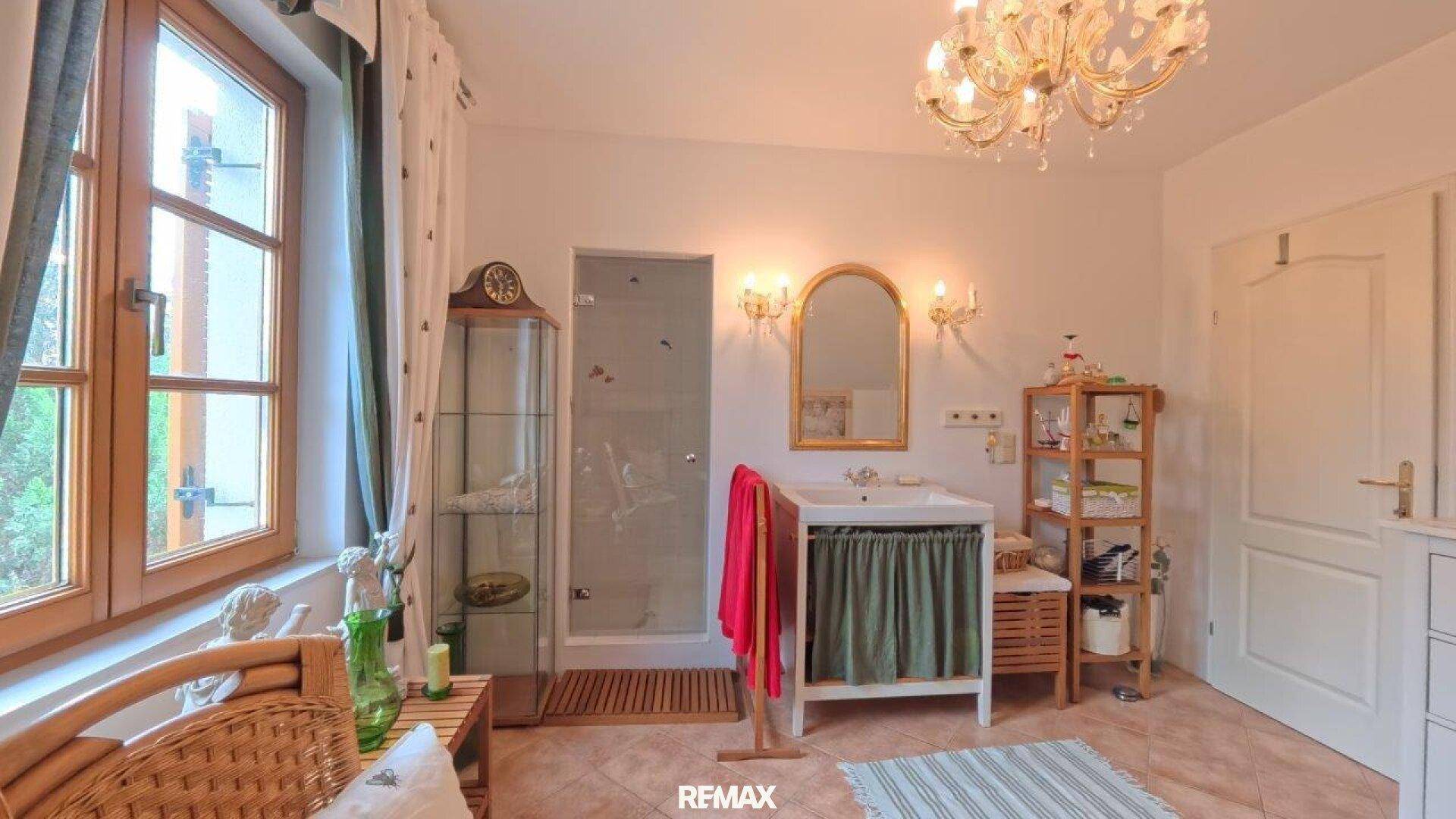 Badezimmer mit Waschtisch, Duschkabine und Fenster im Dachgeschoss.