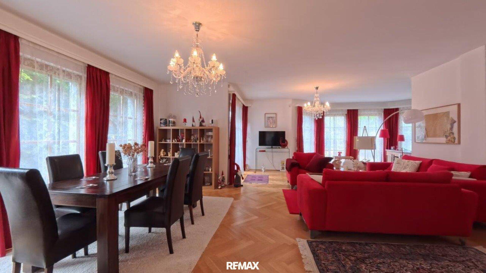Eleganter Essbereich mit großem Holztisch, dunklen Stühlen und Kronleuchter.