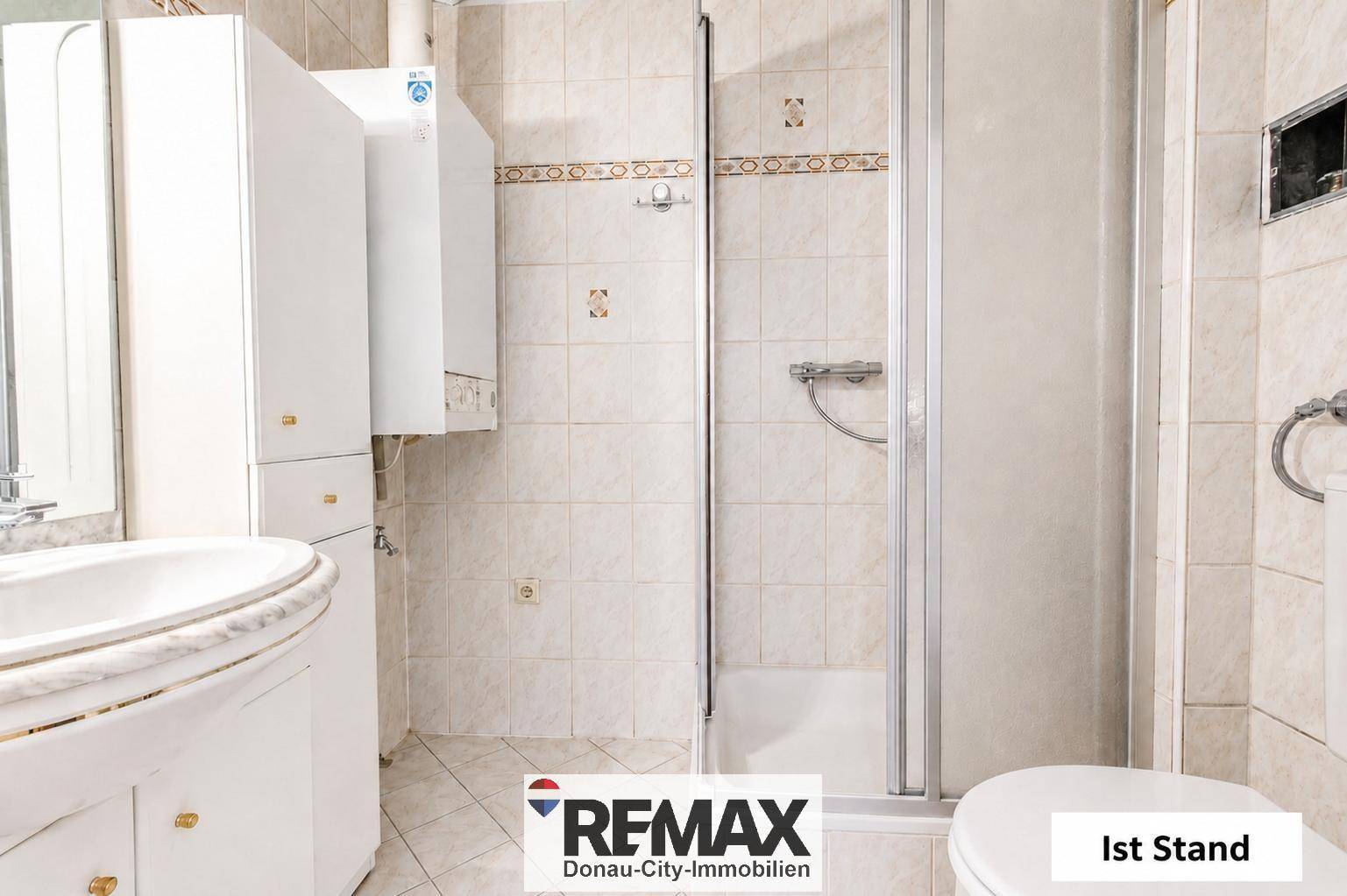Gefliestes Badezimmer mit Dusche, Waschbecken und Toilette im Ist-Zustand.
