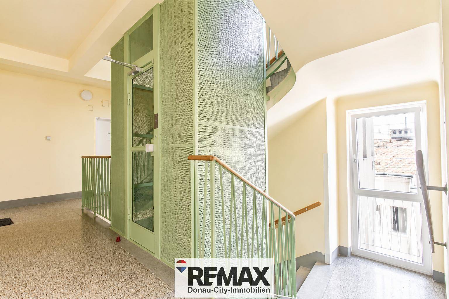Heller Treppenhausbereich mit einem modernen Aufzug und Geländer in einem Mehrfamilienhaus.