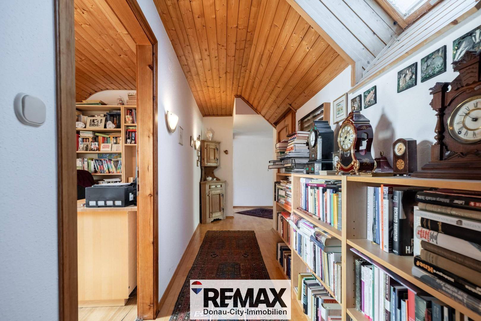 Langer Flur mit Bücherregalen, Holzvertäfelung und Blick ins Arbeitszimmer.