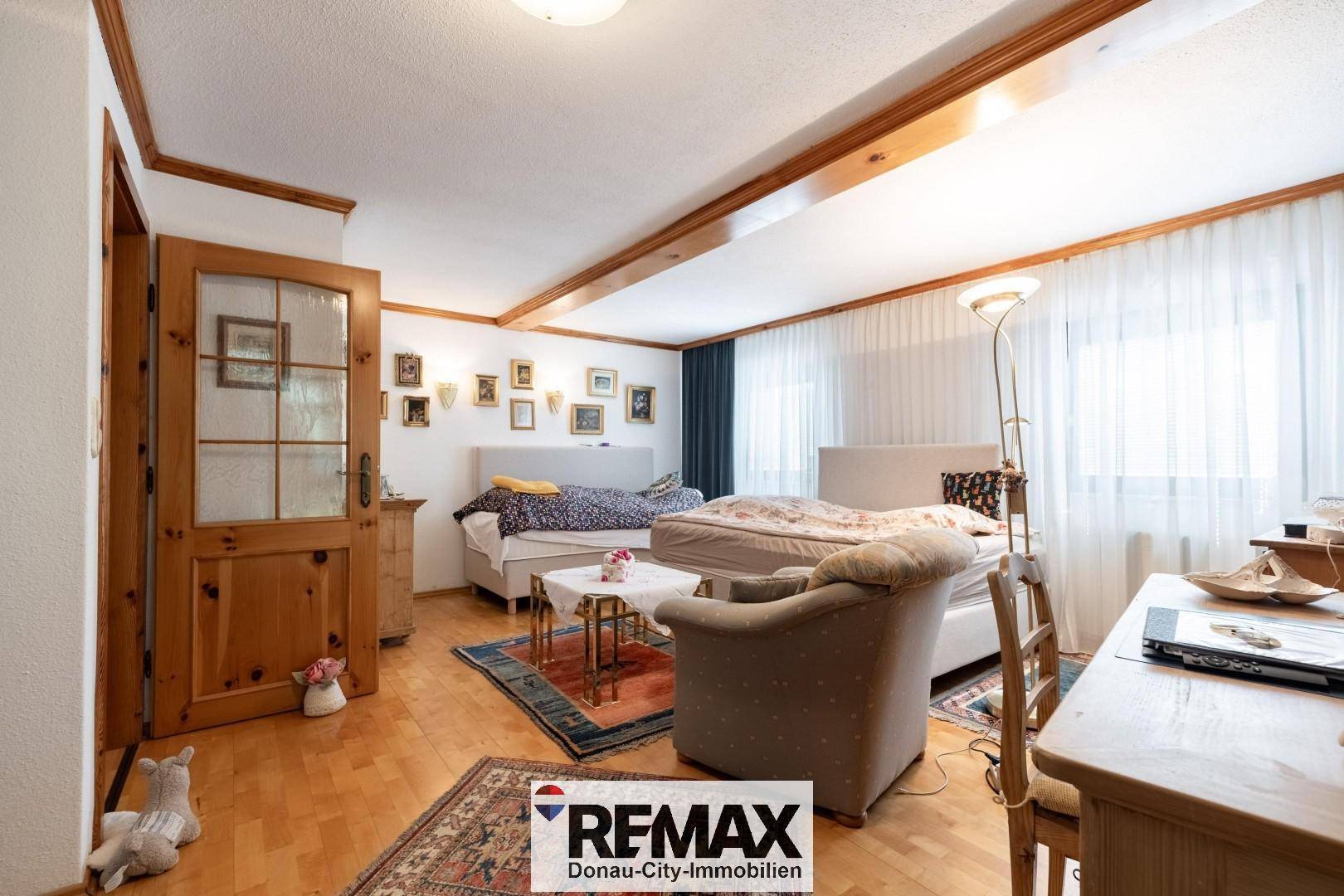Geräumiges Schlafzimmer mit mehreren Betten, Holzboden und großen Fenstern.