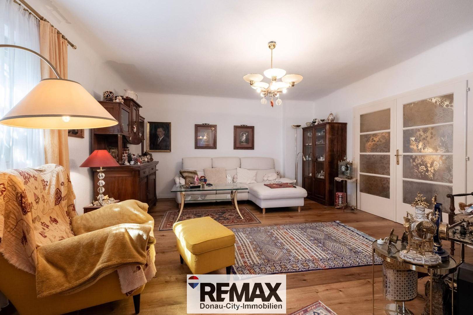 Geräumiges Wohnzimmer mit bequemer Couch, Holzboden und traditioneller Einrichtung.
