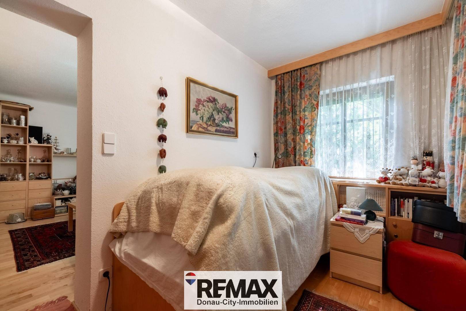 Gemütliches Schlafzimmer mit Holzboden, Fenster und Blick in den angrenzenden Raum.