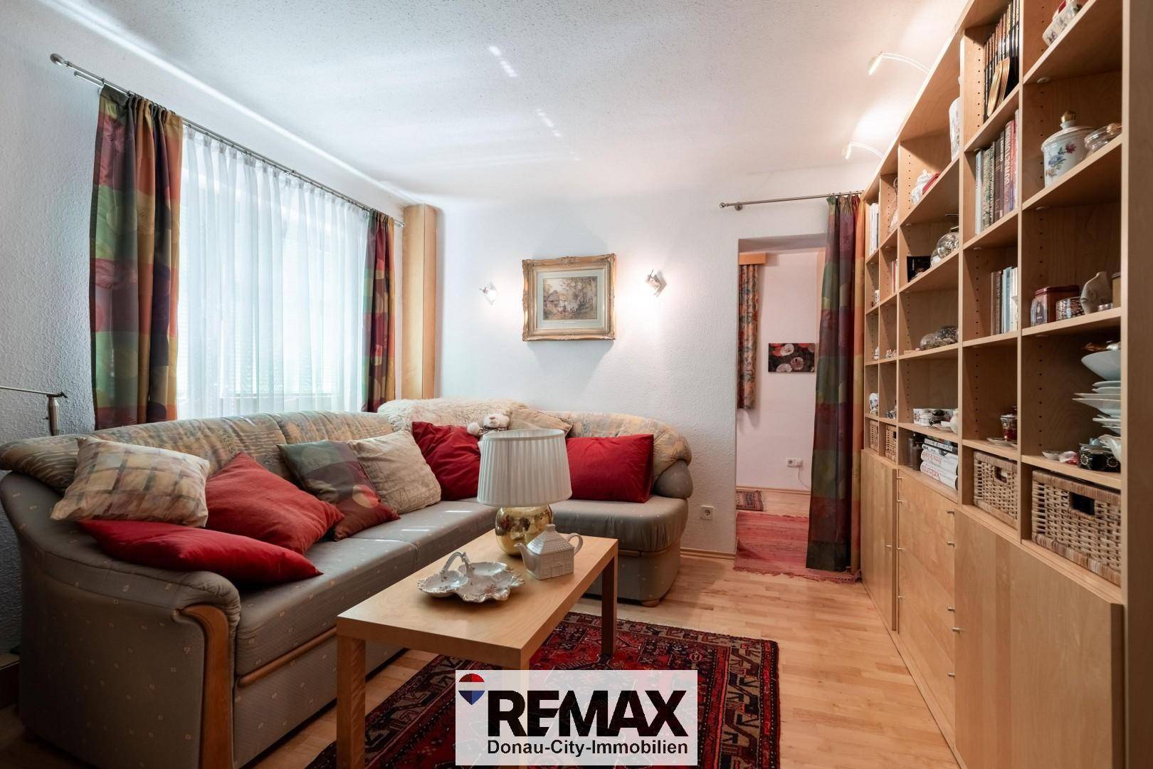 Gemütliches Wohnzimmer mit Sofa, Holzboden und einer großen Bücherwand.