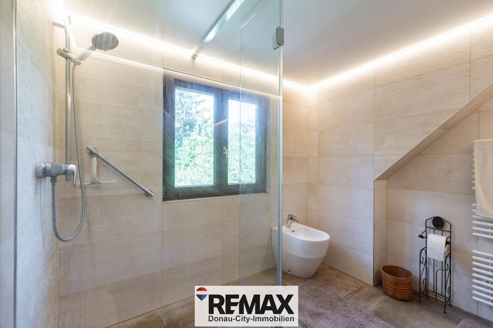 Modernes Badezimmer mit ebenerdiger Dusche, Bidet und Fenster für Tageslicht.