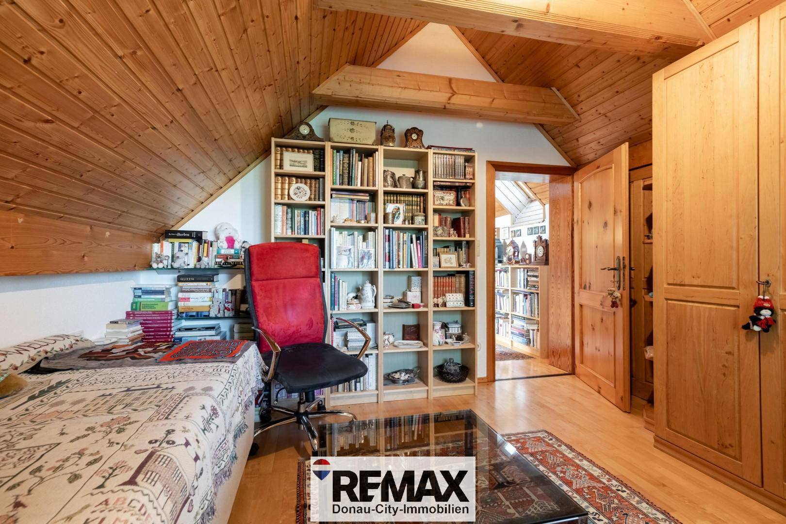 Gemütliches Schlafzimmer mit Holzvertäfelung, Bücherregal und traditionellem Kleiderschrank.