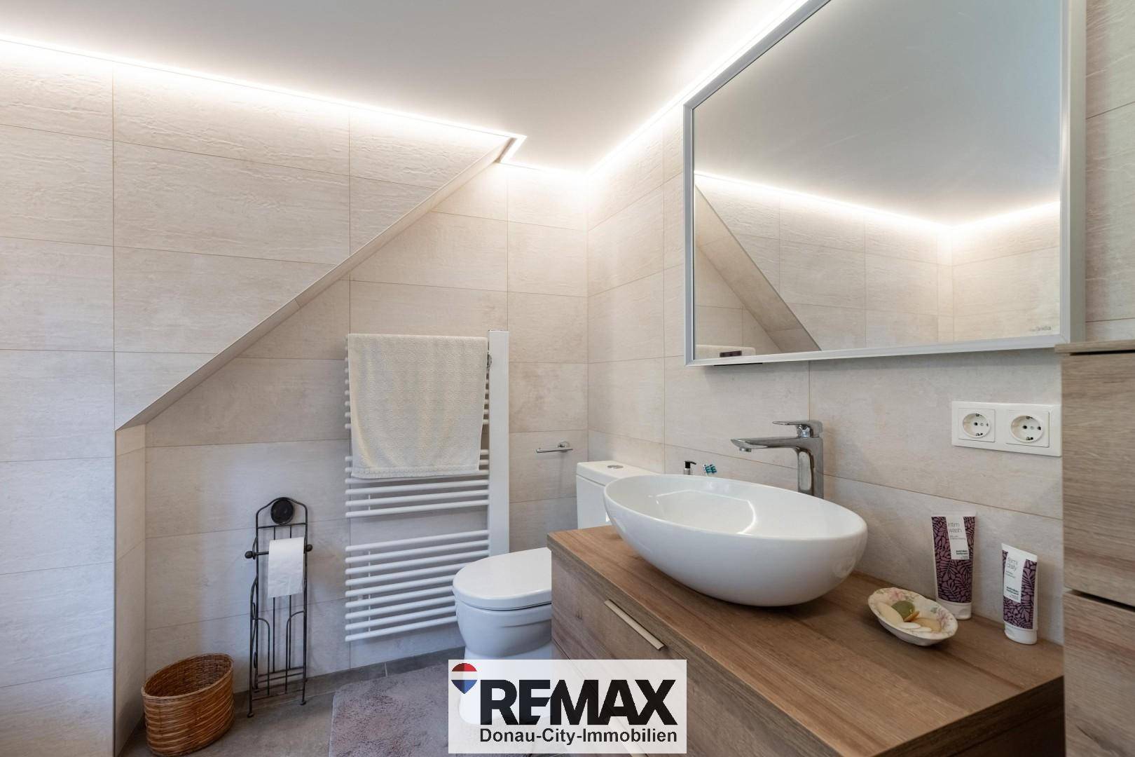 Helles Badezimmer mit modernem Waschtisch, Toilette und beheiztem Handtuchhalter.