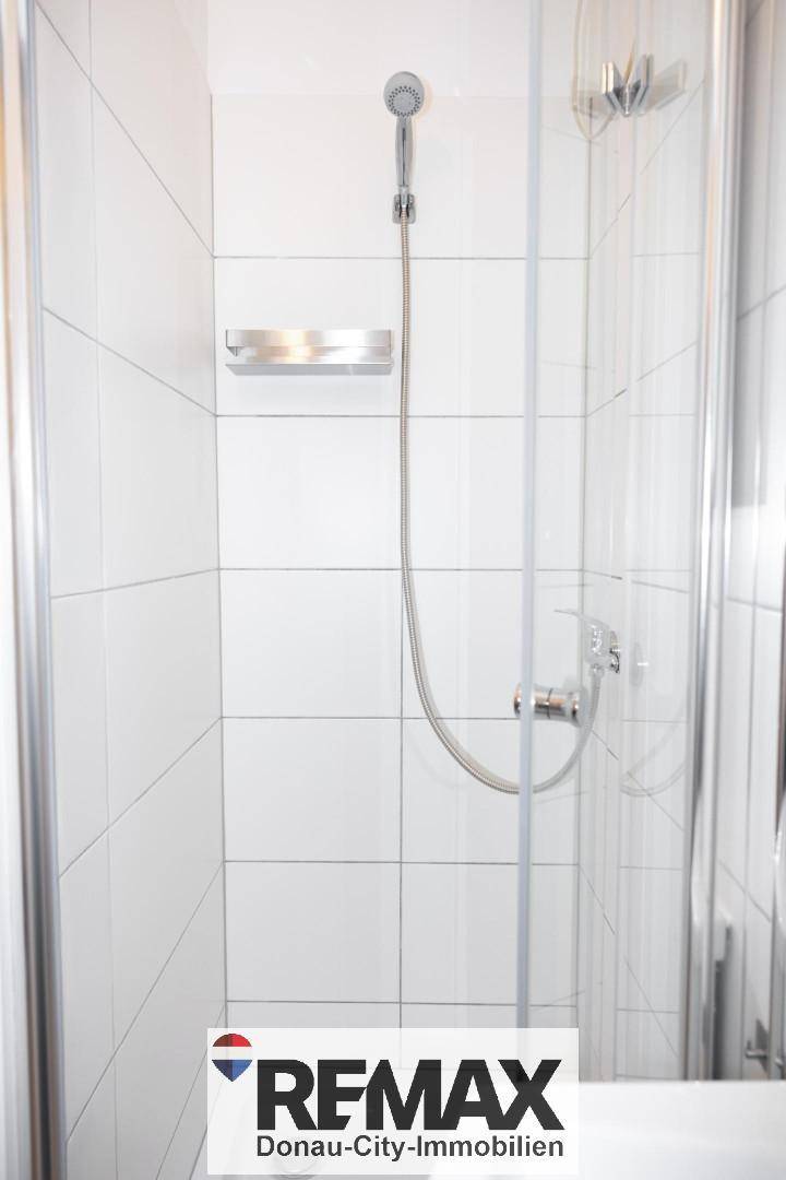 Moderne Duschkabine mit weißen Fliesen und Glasabtrennung im Badezimmer.