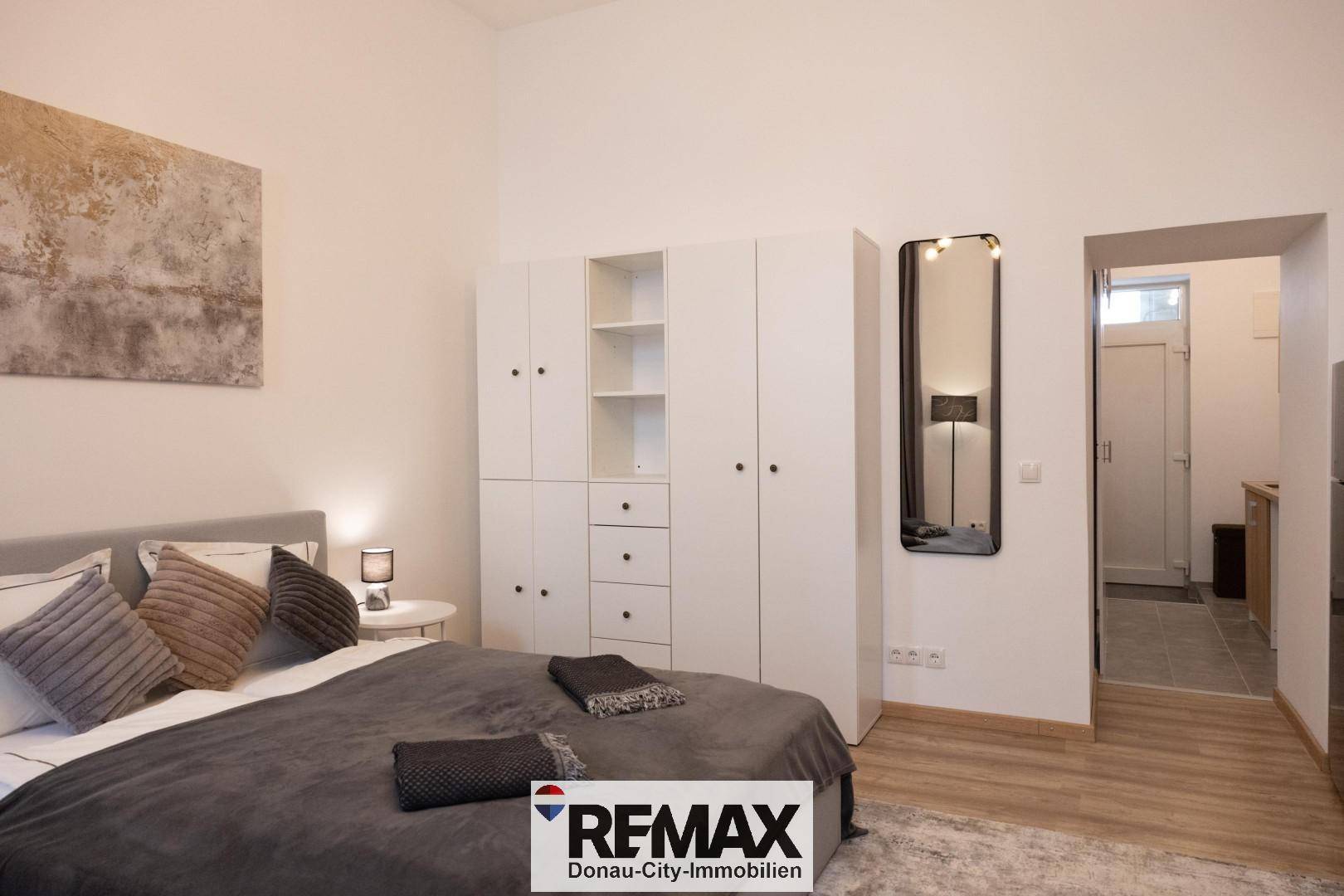 Schlafzimmer mit weißem Kleiderschrank und Zugang zu einem angrenzenden Flurbereich.