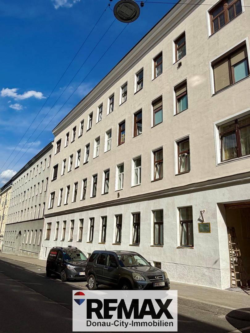 Historisches Wohngebäude mit klassischer Fassade und vielen Fenstern an einer Stadtstraße.