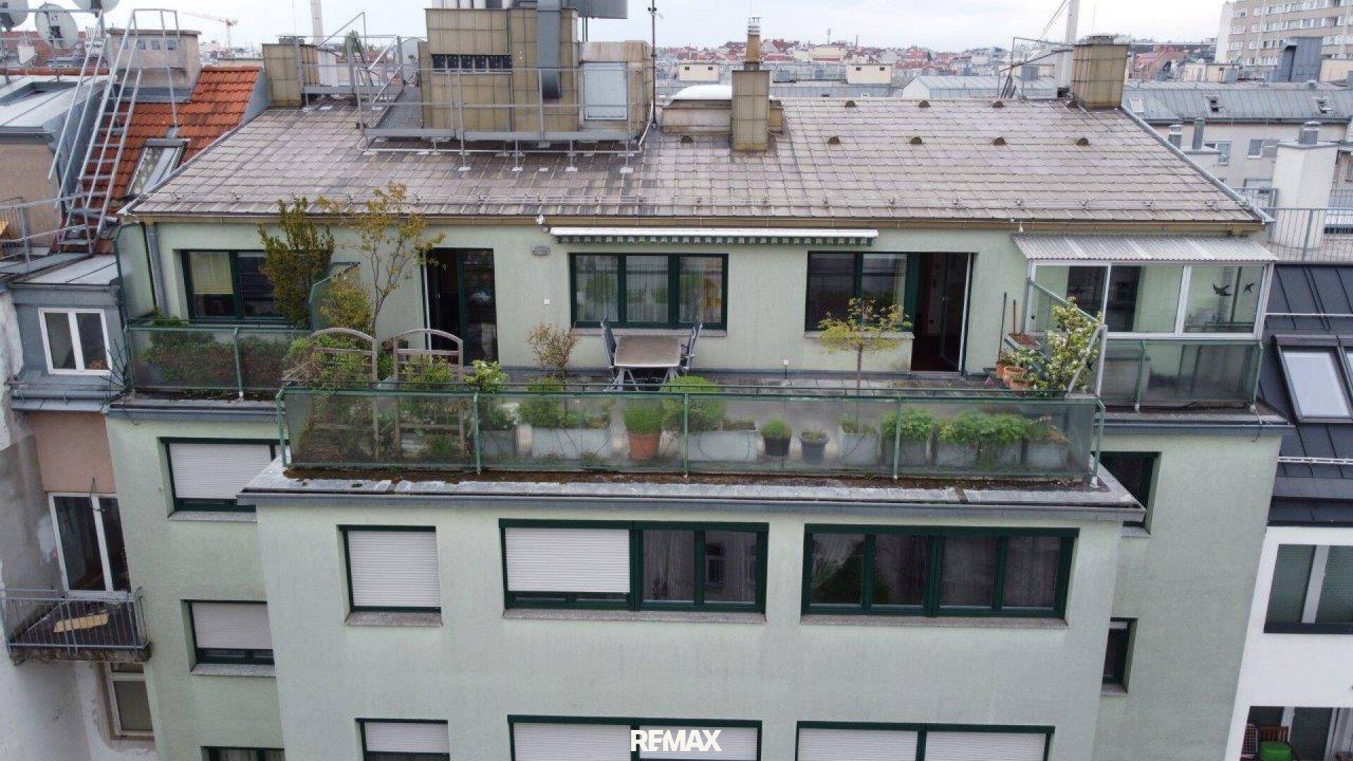 Dachterrasse mit Pflanzen und Sitzgelegenheiten auf einem Mehrfamilienhaus in der Stadt.