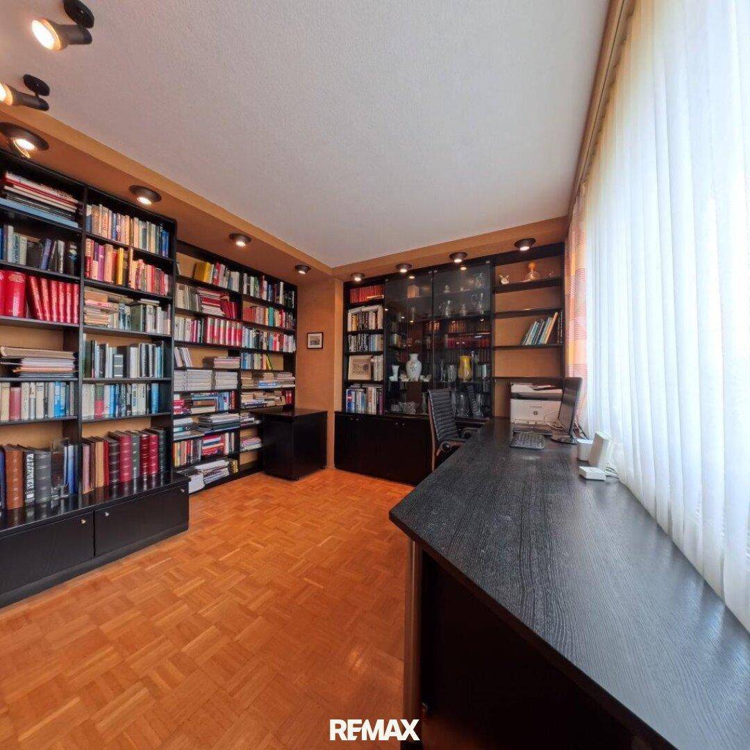 Arbeitszimmer mit vielen Bücherregalen, Schreibtisch und Parkettboden.