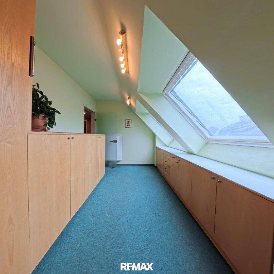 Dachgeschossraum mit Teppichboden, Dachfenster und Einbauschränken unter der Schräge.
