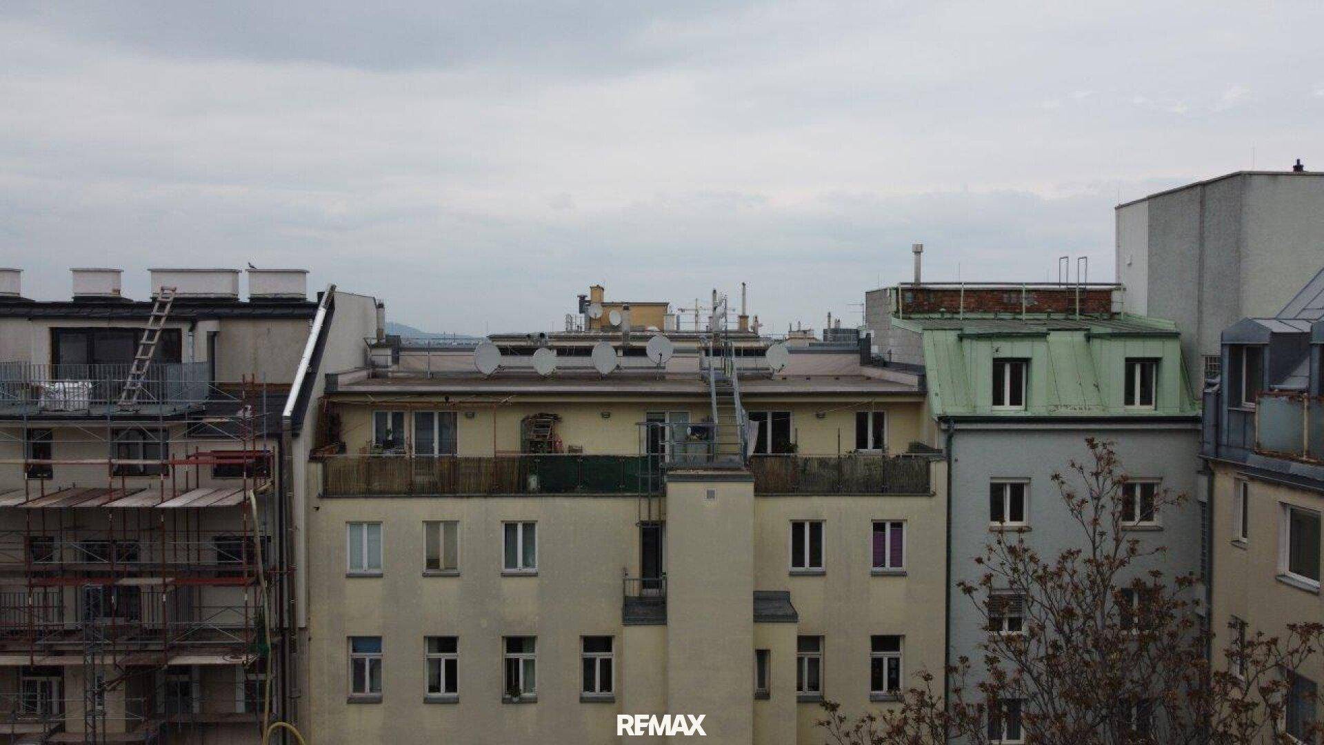 Mehrere Wohngebäude mit unterschiedlichen Fassaden und Dächern unter einem bewölkten Himmel.