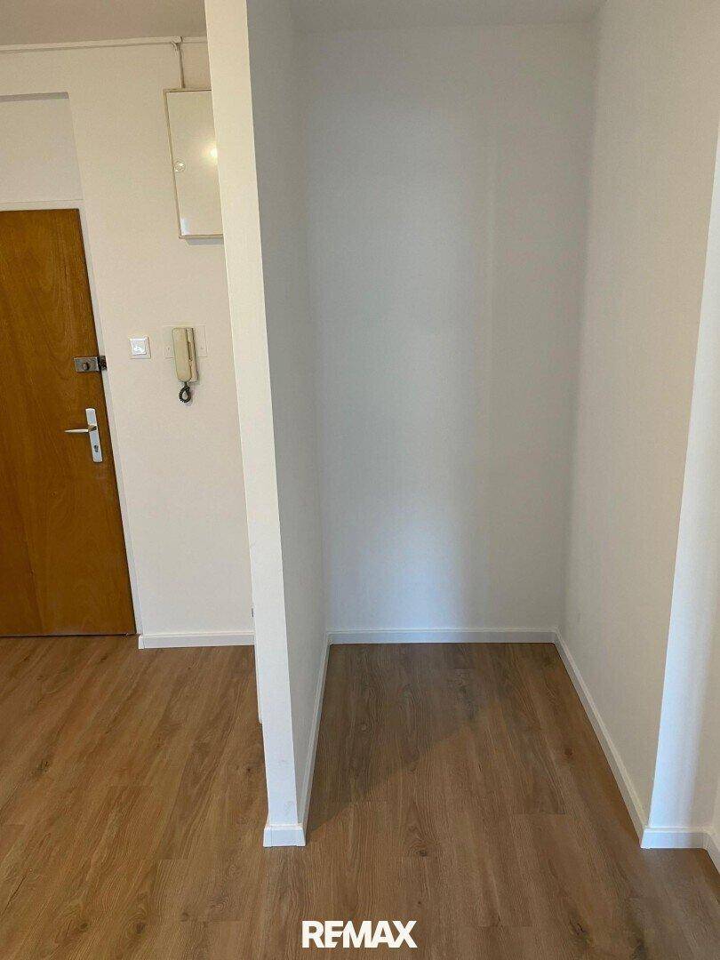 Heller Flur mit Laminatboden und einer praktischen Nische, ideal für Garderobe oder Stauraum.