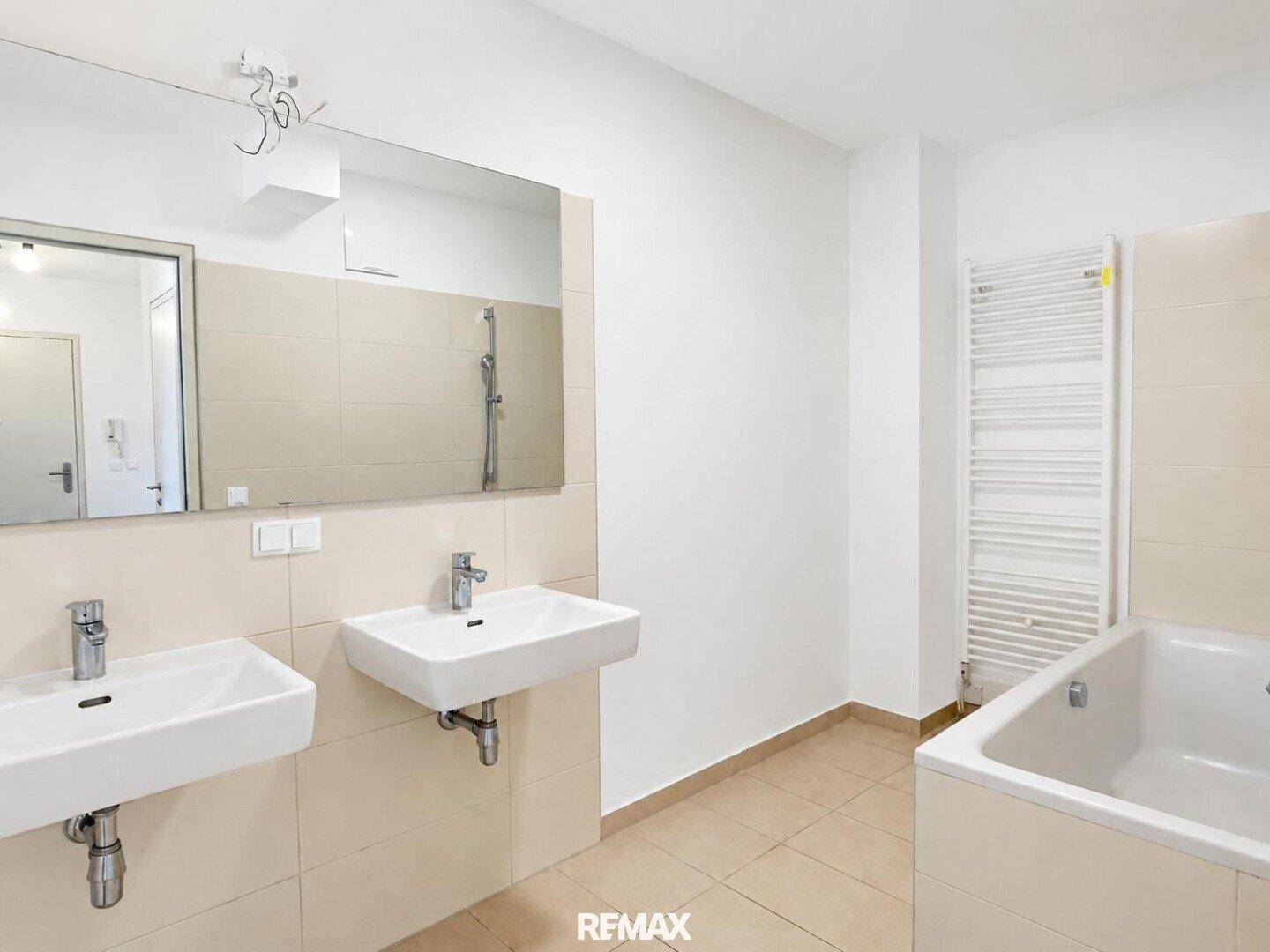 Modernes Badezimmer mit Doppelwaschbecken, Badewanne und beheiztem Handtuchhalter.