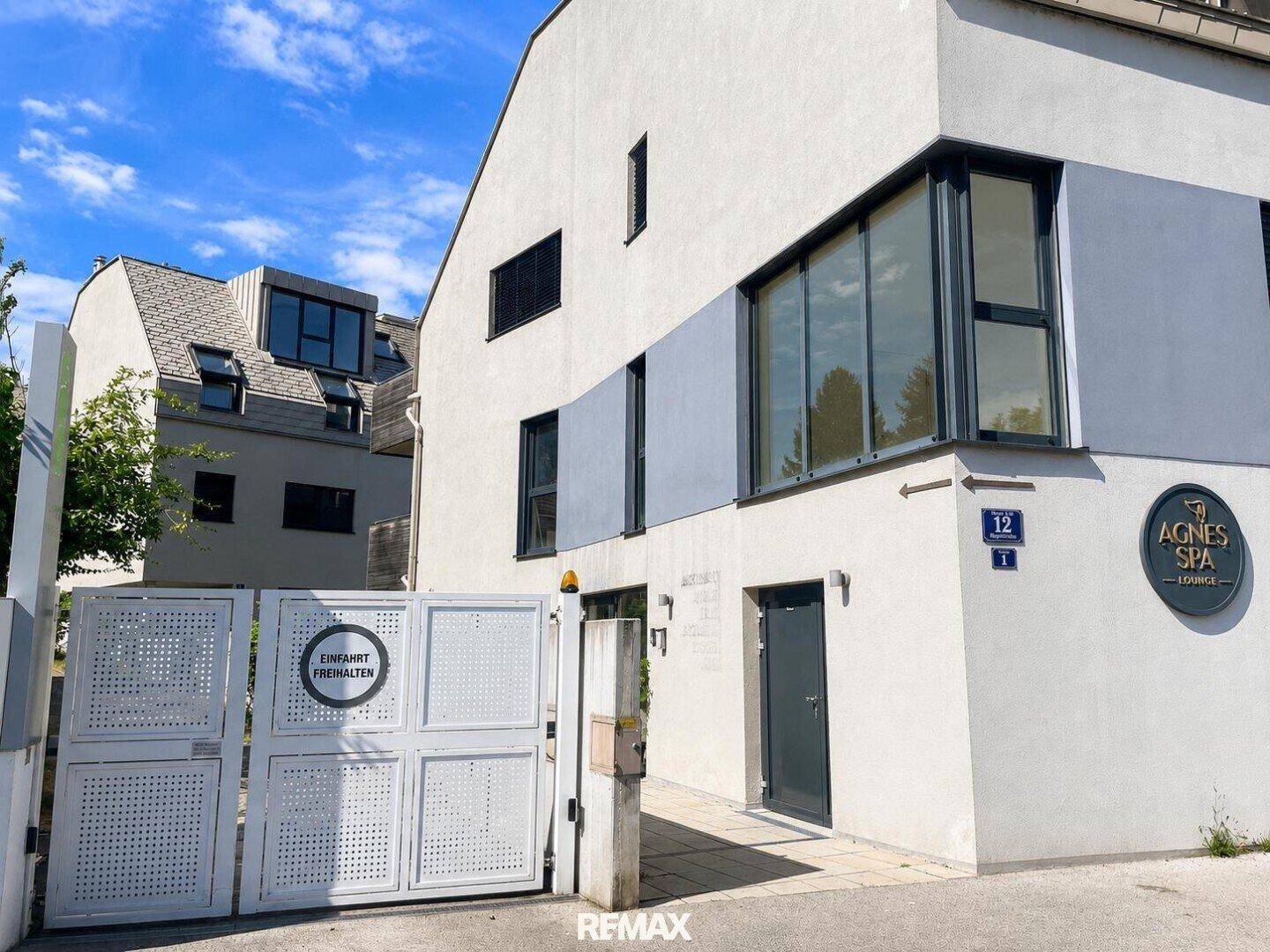 Moderne Gebäudefassade mit Eingangstor und Beschilderung für ein Spa-Lounge-Geschäft.
