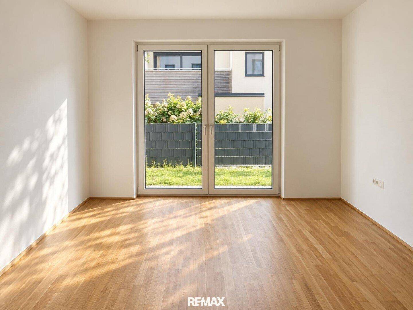 Helles Zimmer mit Holzboden und großen Fenstertüren, die den Blick in den Garten freigeben.