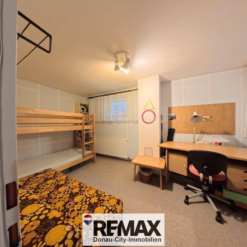 Kinderzimmer mit Etagenbett, Schreibtisch und Fenster, bietet Platz zum Schlafen und Lernen.