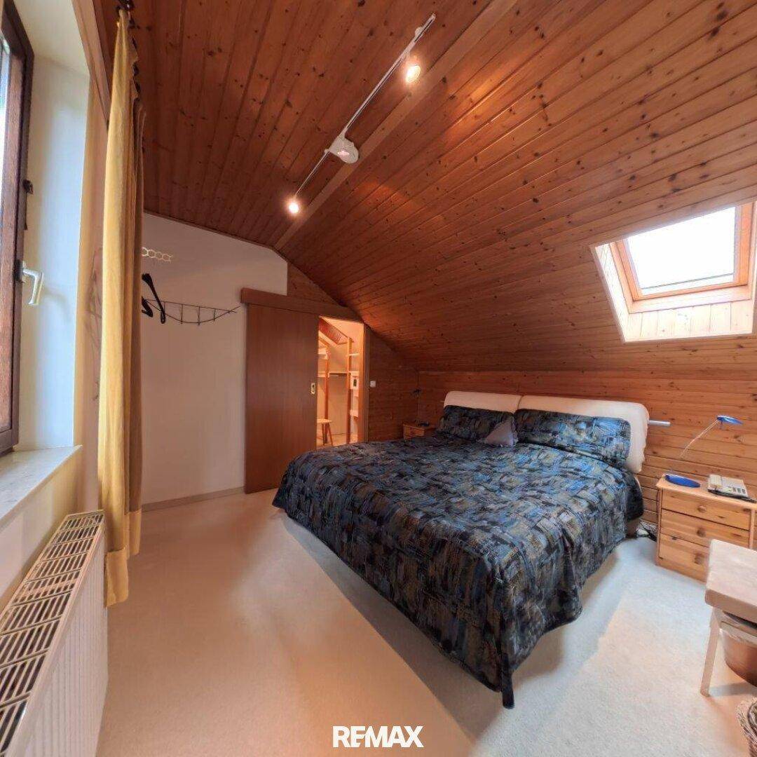 Helles Schlafzimmer im Dachgeschoss mit Holzdecke, Dachfenster und integrierten Holzschränken.