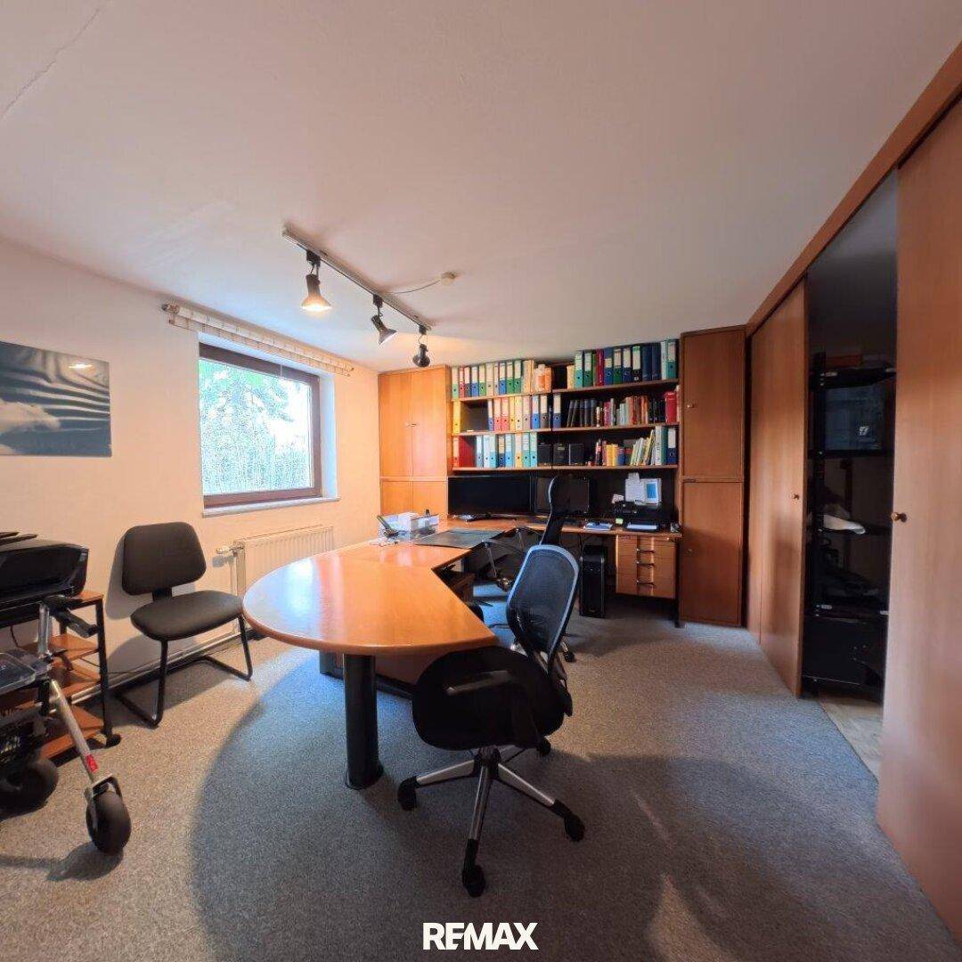 Geräumiges Büro mit großem Schreibtisch, Bürostühlen und integrierten Bücherregalen für viel Stauraum.