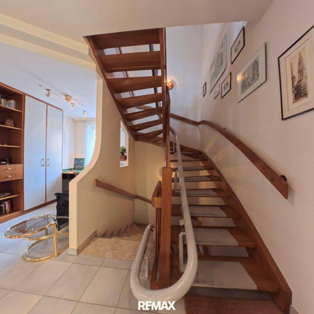 Elegante Holztreppe mit Handlauf, die die verschiedenen Ebenen des Hauses miteinander verbindet.