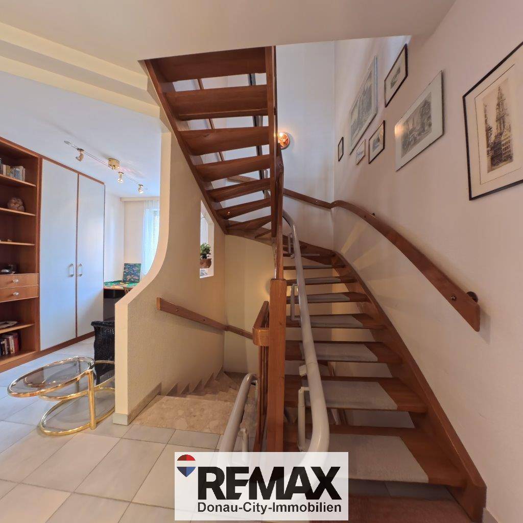 Elegante Holztreppe mit geschwungenem Geländer, die in die oberen Stockwerke führt.