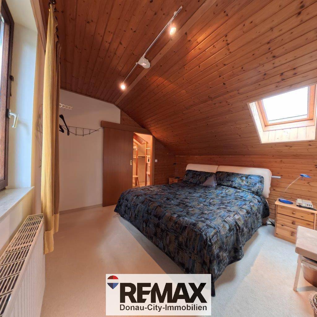 Helles Schlafzimmer im Dachgeschoss mit Holzdecken, Doppelbett und Dachfenster.