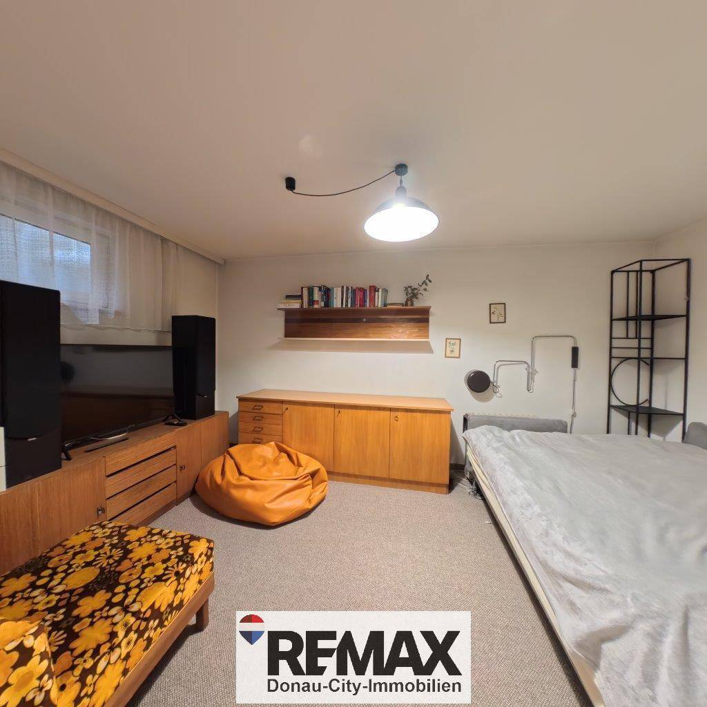 Vielseitiger Raum mit Bett, Sitzgelegenheiten und Holzmöbeln, ideal als Gäste- oder Hobbyzimmer.