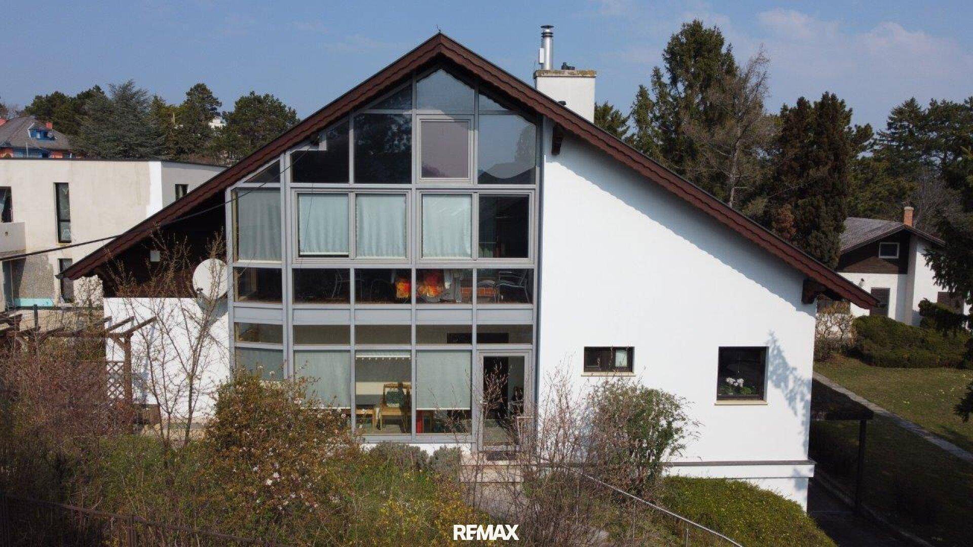 Frontale Ansicht des modernen Hauses mit beeindruckender Glasfront und klaren architektonischen Linien.