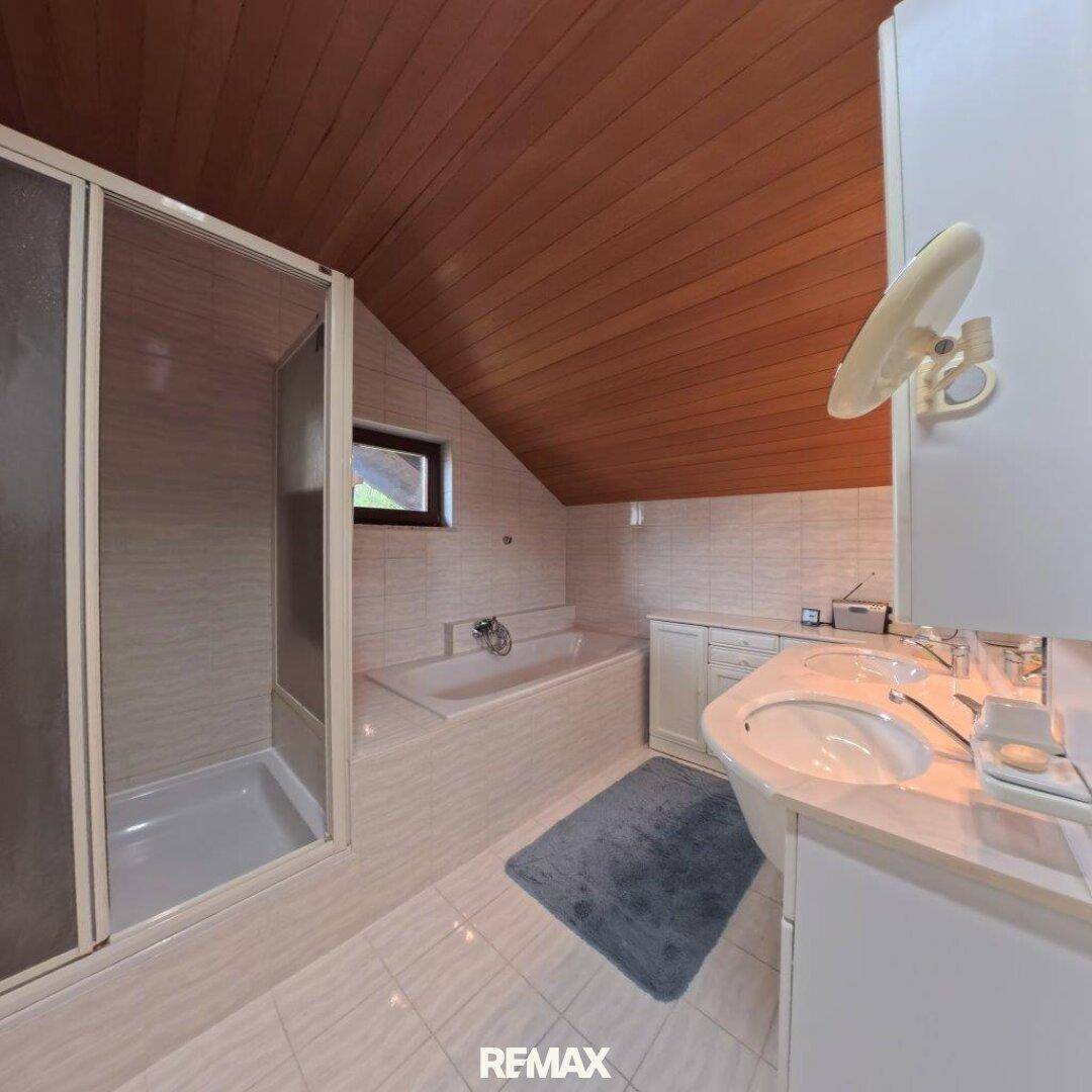 Badezimmer im Dachgeschoss mit Holzdecke, Badewanne, Duschkabine und Einzelwaschbecken.