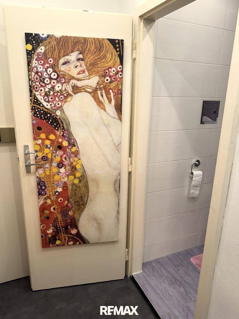 Badezimmertür mit Kunstwerk und Blick auf die Toilette.
