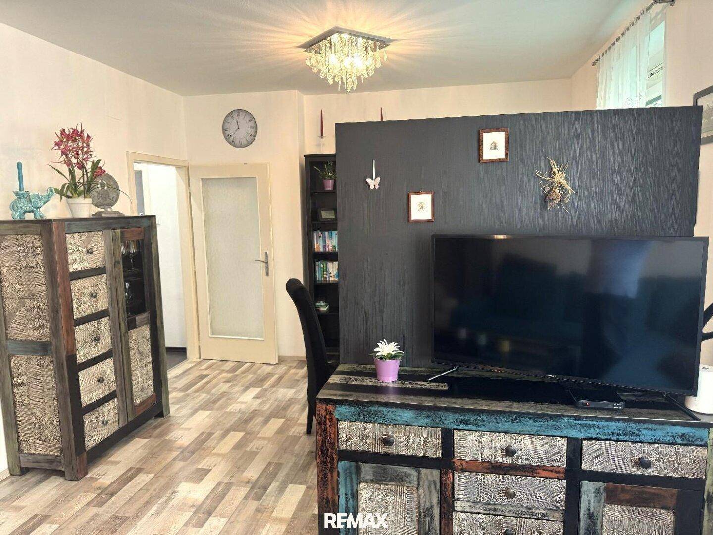 Wohnbereich mit Fernseher, Sideboard und dekorativen Elementen.