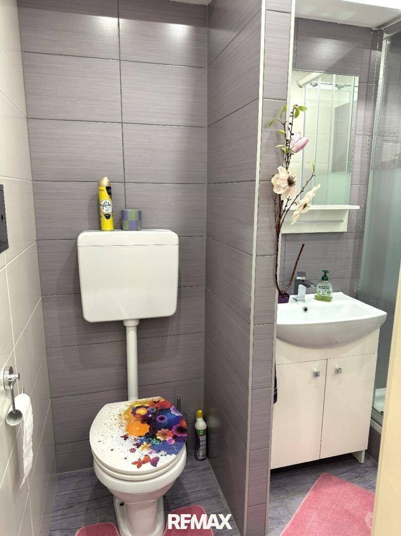 Kleines Badezimmer mit Toilette, Waschbecken und Duschkabine.