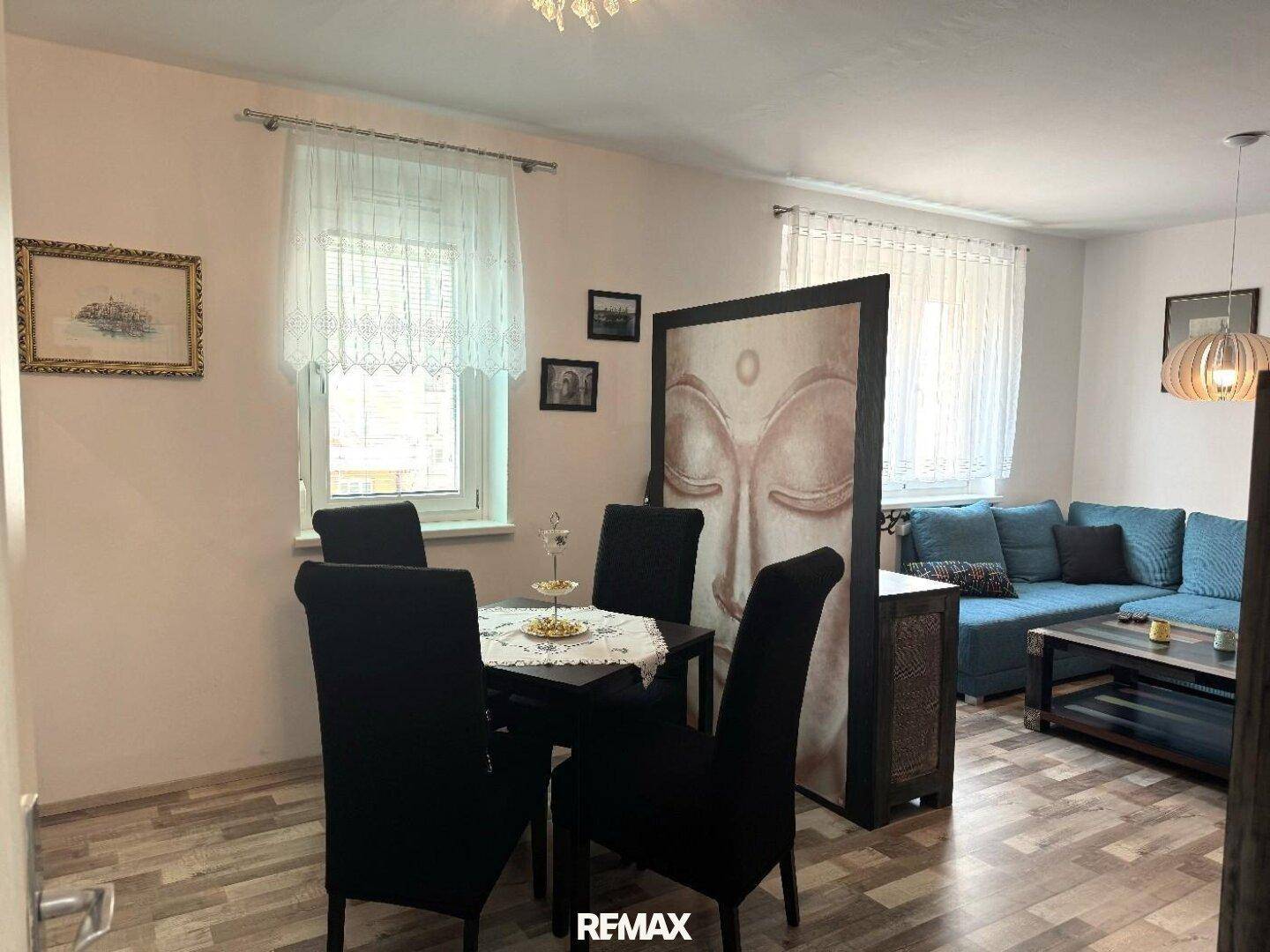 Kombinierter Wohn- und Essbereich mit Esstisch, Stühlen und Sofa im Hintergrund.