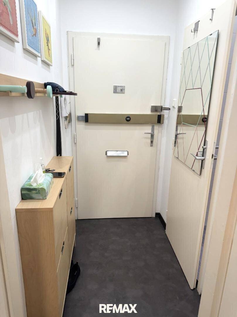 Heller Eingangsbereich mit Sicherheitstür, Schuhschrank und Spiegel.