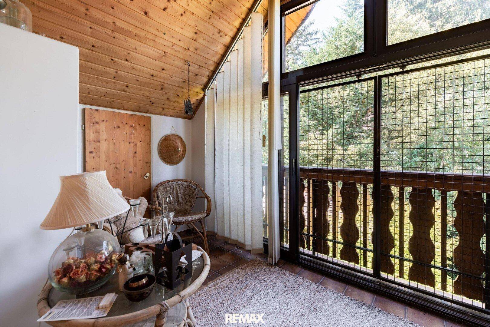 Heller, verglaster Balkon mit Holzdach und Blick ins Grüne, ideal zum Entspannen.