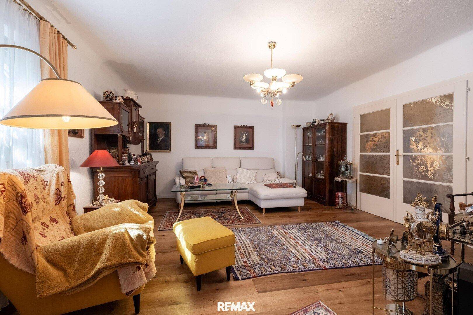 Geräumiges Wohnzimmer mit bequemer Couch, Holzboden und traditioneller Einrichtung.