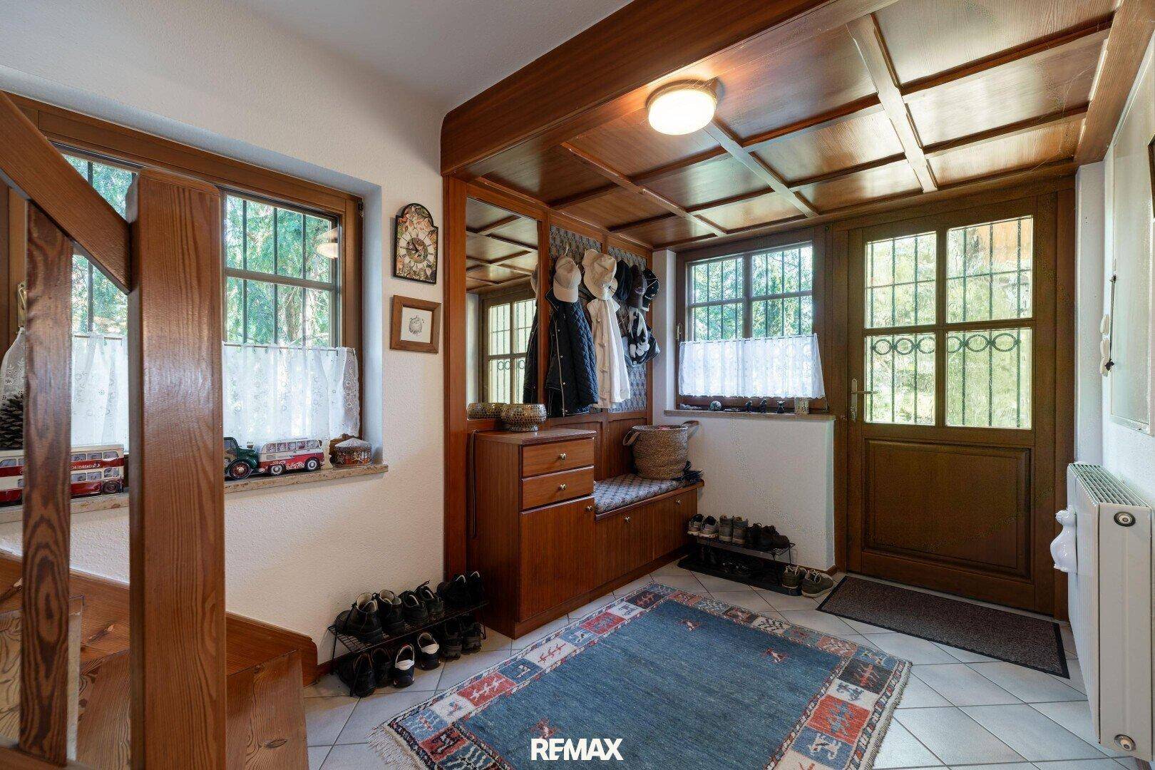 Gemütlicher Eingangsbereich mit Holztäfelung, Garderobe und Sitzbank, ideal für Schuhe.