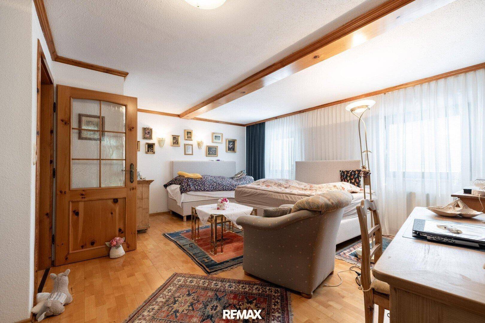Geräumiges Schlafzimmer mit zwei Betten, Sitzgelegenheiten und einem Schreibtischbereich.