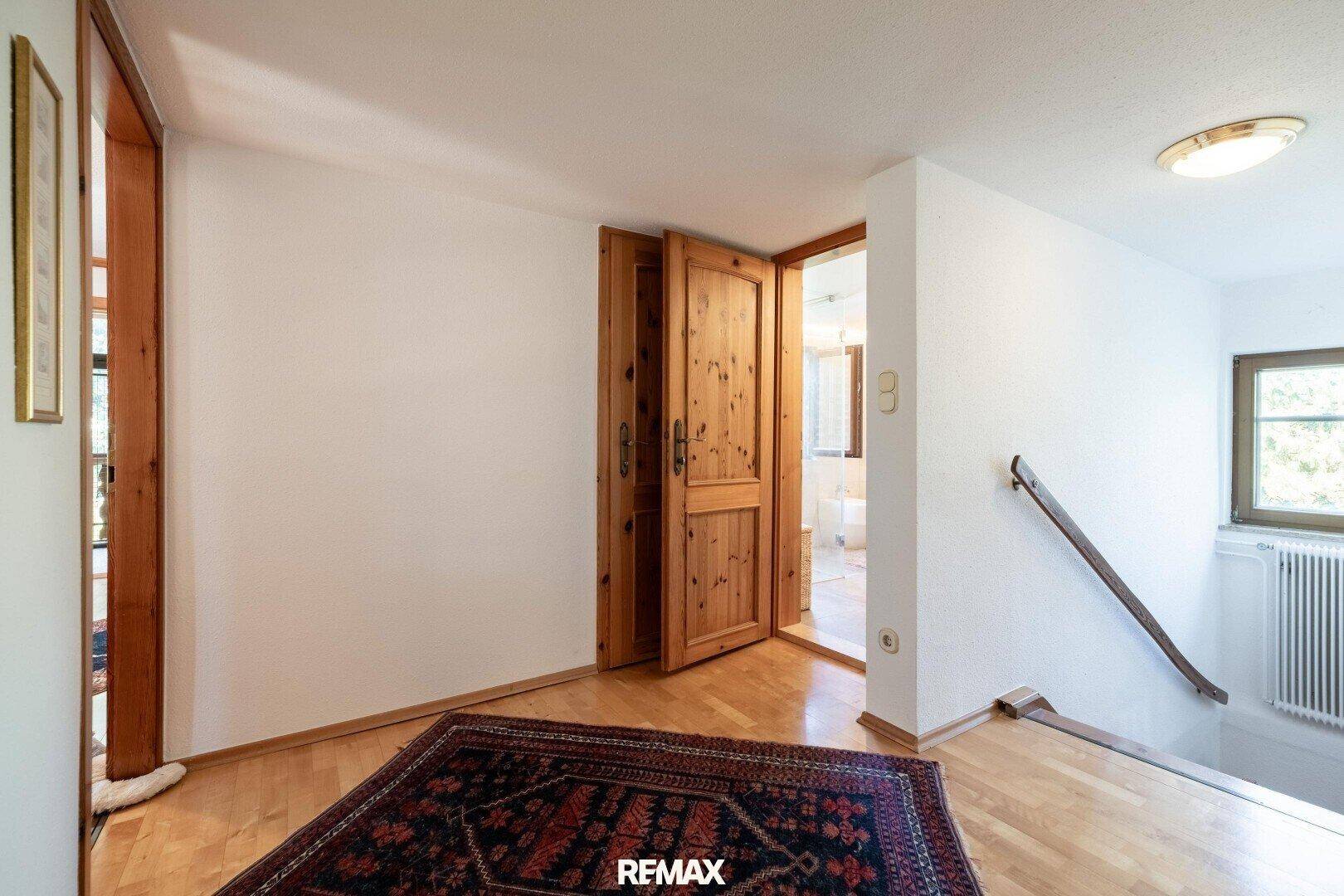 Heller Flur mit Holzboden, Teppich und Zugang zu einem Badezimmer im oberen Stockwerk.