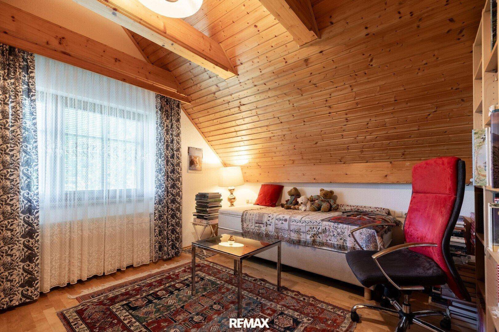 Gemütliches Schlafzimmer im Dachgeschoss mit Holzdecke, Fenster und traditioneller Einrichtung.