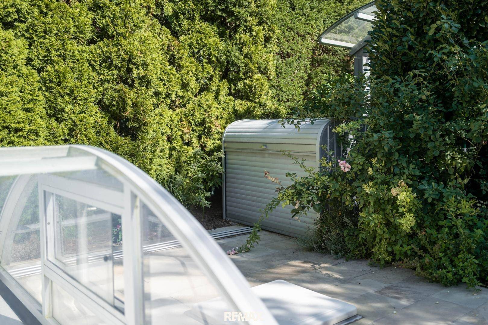 Gartenbereich mit praktischem Geräteschuppen und der Abdeckung des Schwimmbeckens.