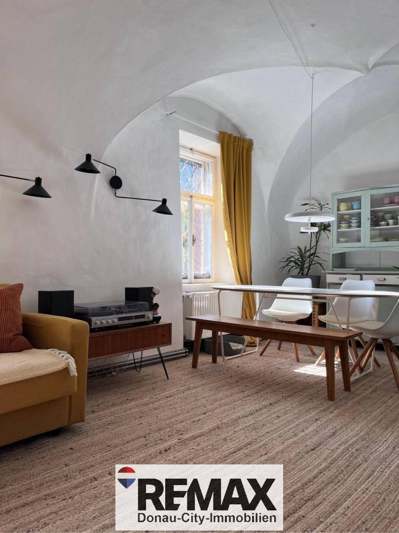 Geräumiger Essbereich mit Holztisch, Sitzbank und gewölbter Decke, hell durch ein großes Fenster.